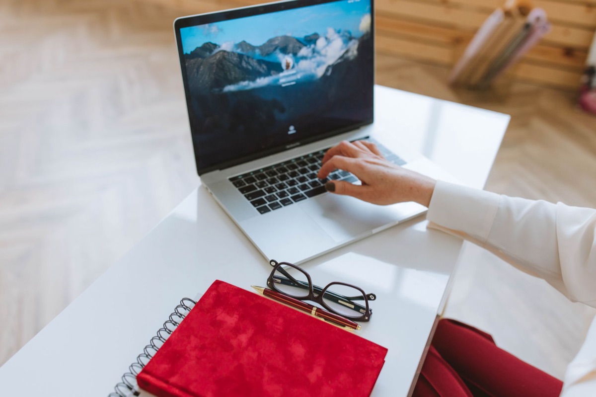 person typing on laptop with notebook open for AI prompt engineering