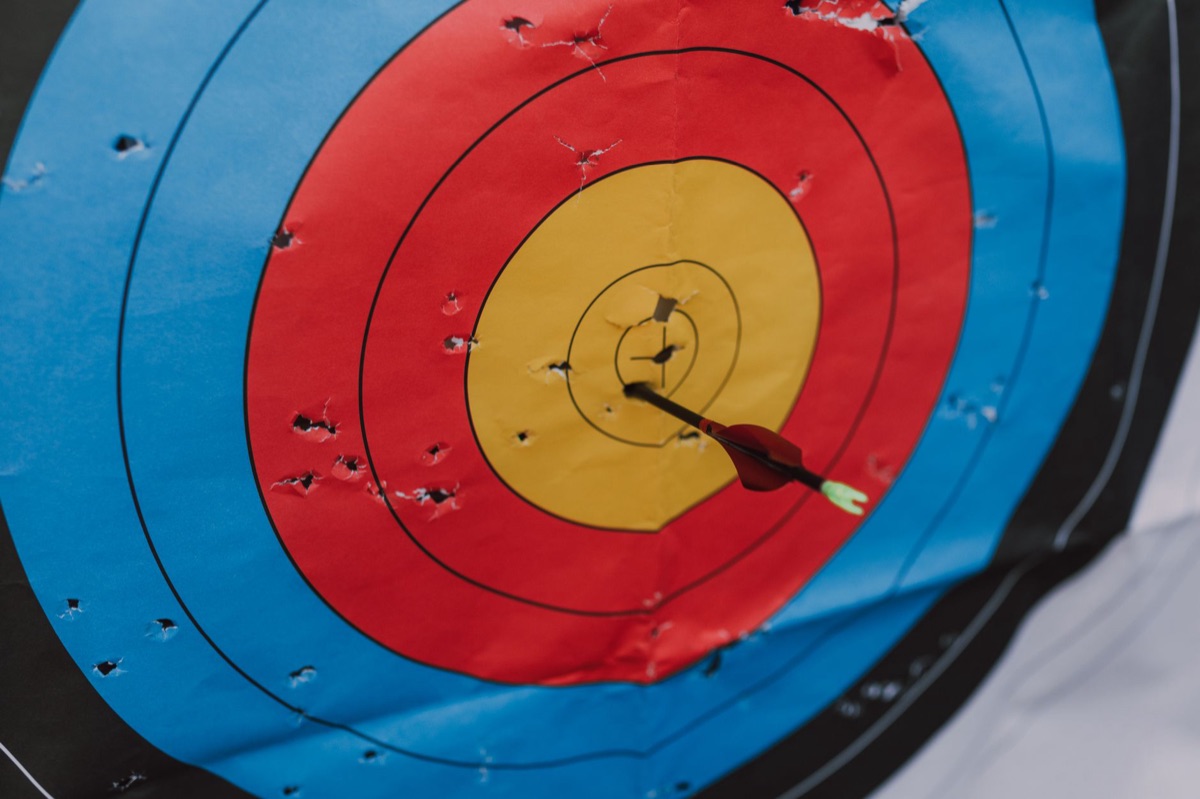 A close-up of an arrow hitting the center of a target bullseye.