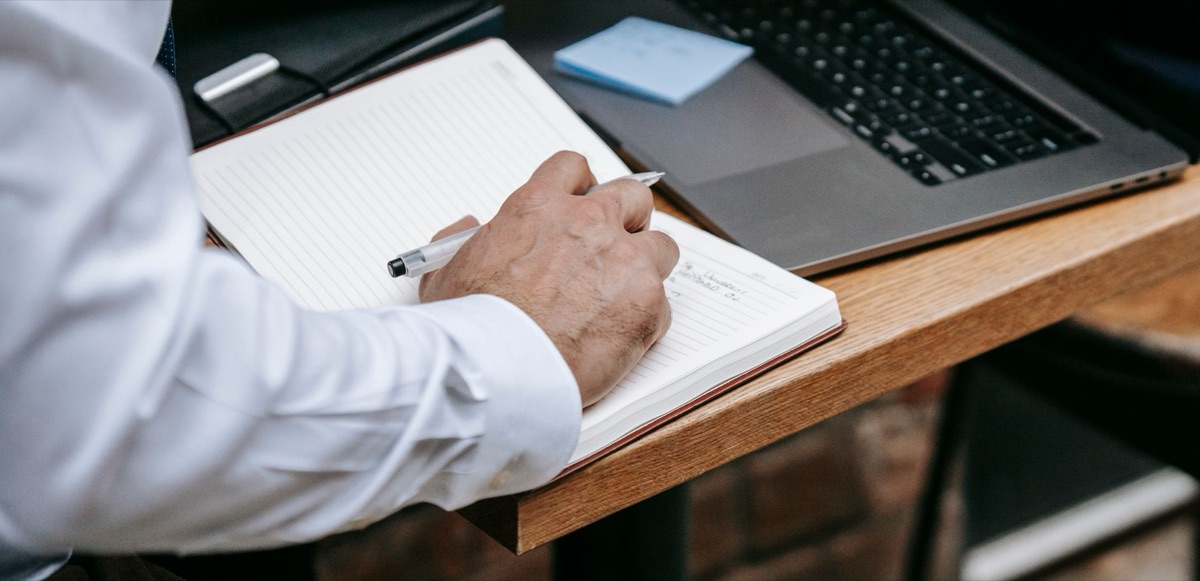 Currículo profissional com notebook e caderno, representando a importância de organizar e apresentar a experiência de uma pessoa que está em transição de carreira.