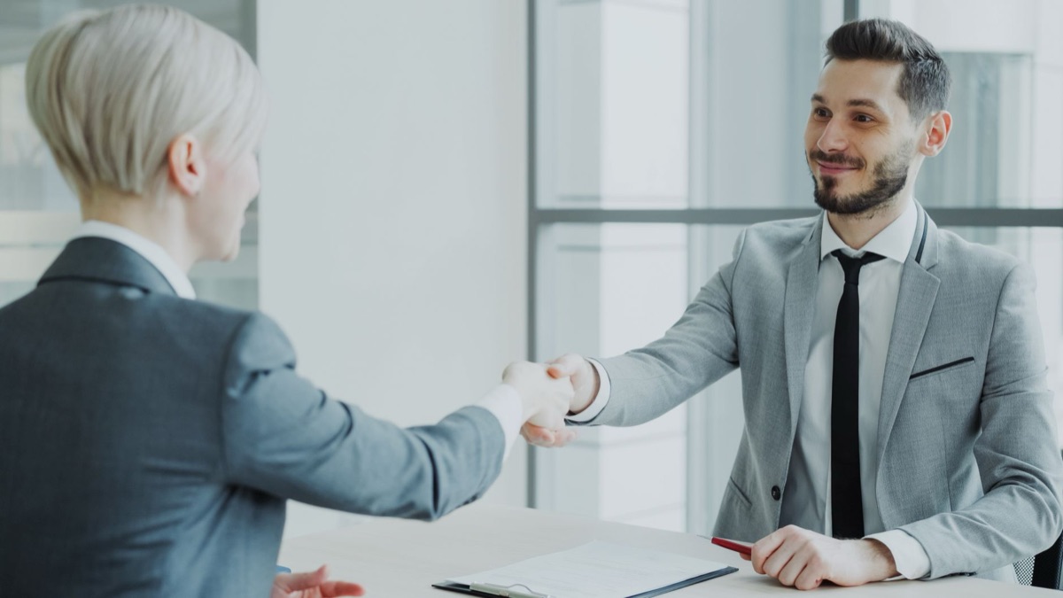 Close up of professional business attire and a handshake representing a job offer.