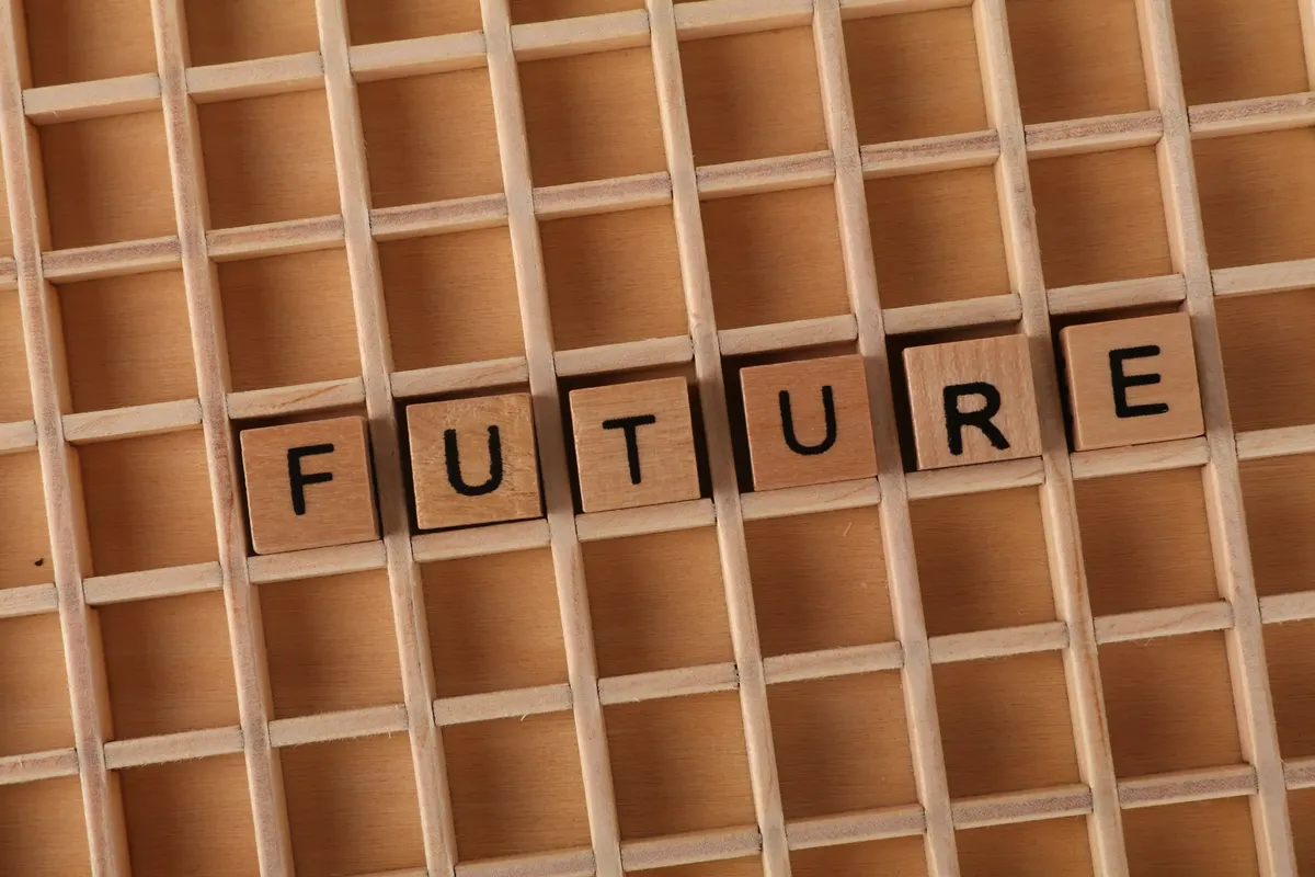 Wooden letter blocks spell 'FUTURE' on a wooden grid background.